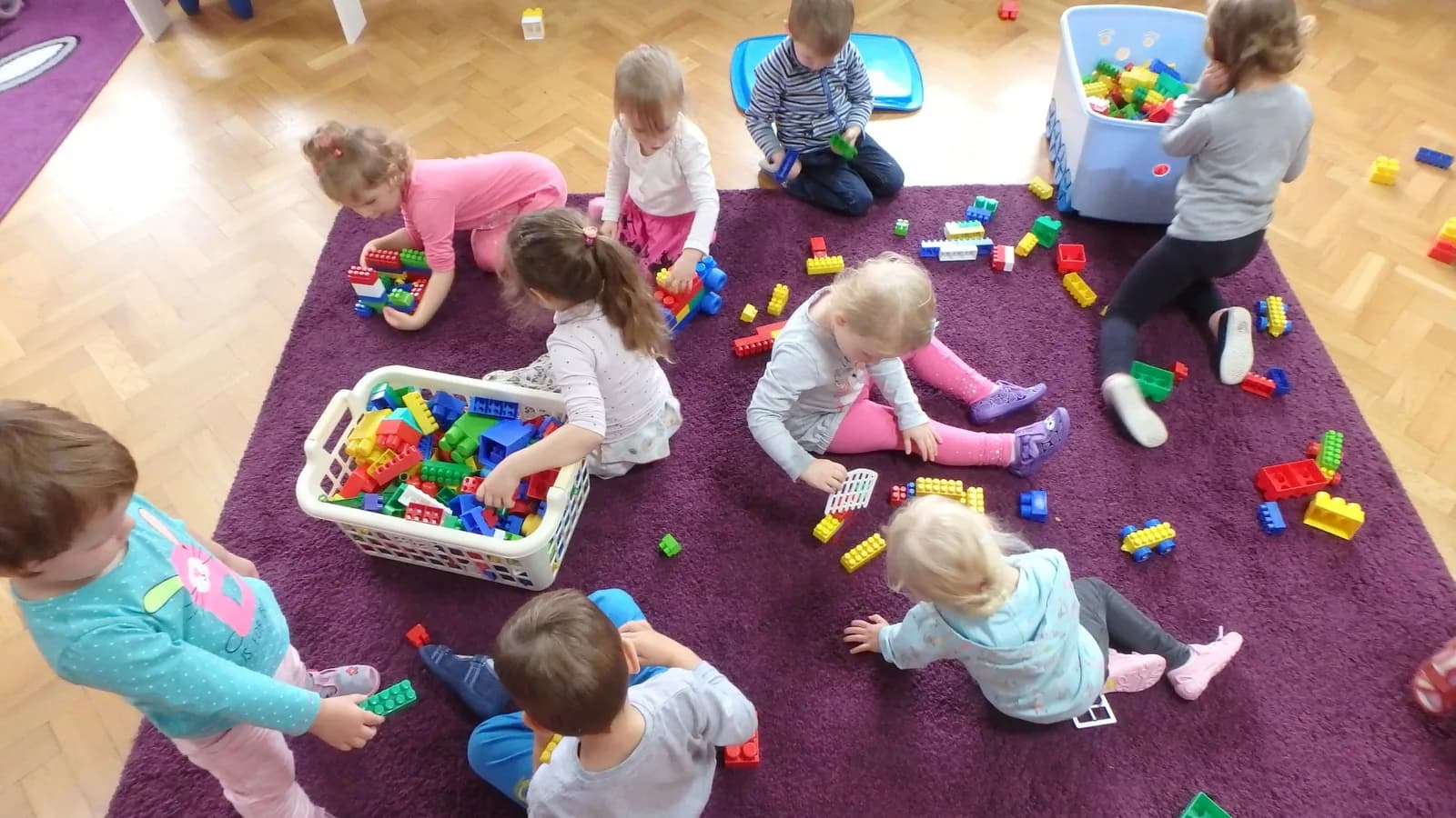 Dzieci bawiące się klockami na dywanie w sali przedszkolnej